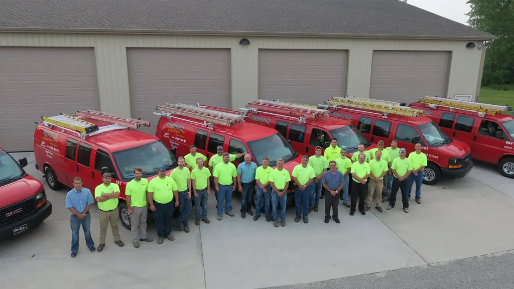 The Nuechterlein Electric crew standing with the fleet of branded service vans outside the shop on List Street in Frankenmuth.