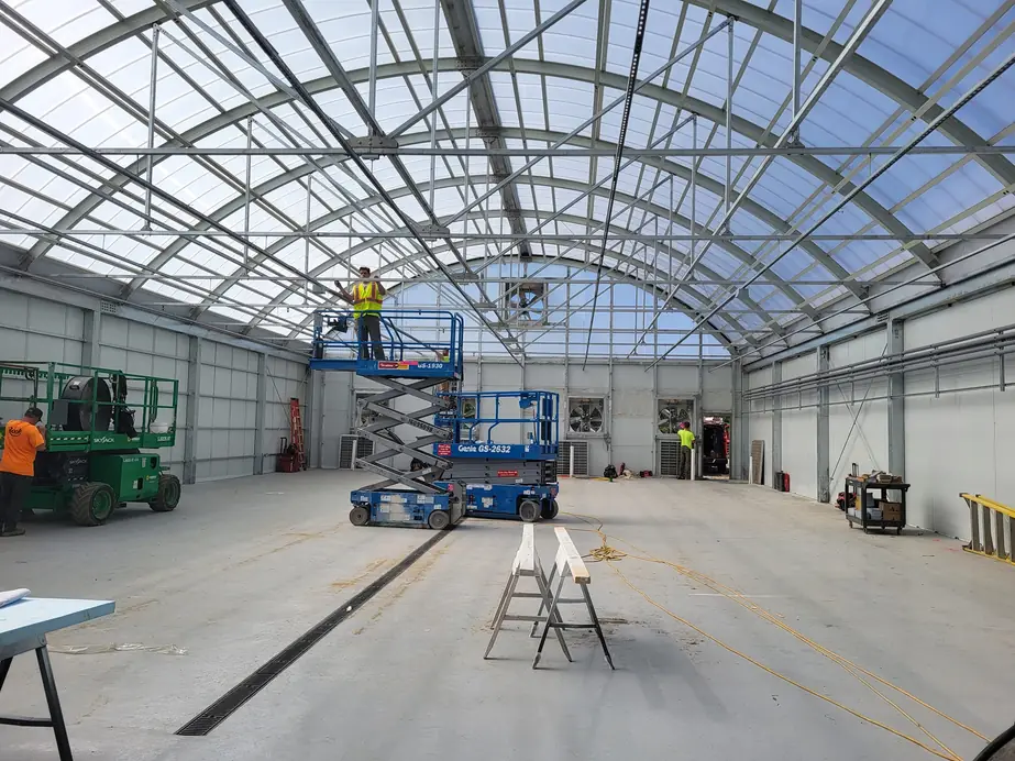 A Nuechterlein Electric crew on scissor lifts running overhead conduit in a large commercial building.